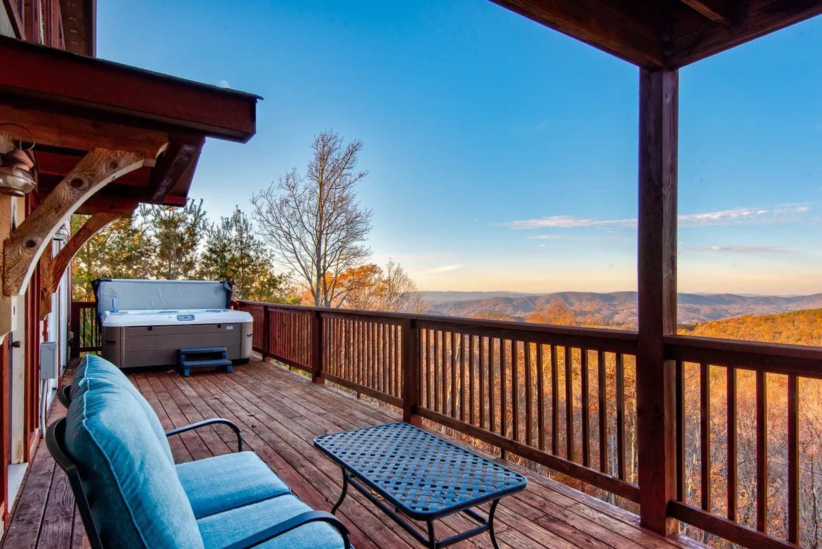 This exterior image features a hot tub and outdoor seating on a deck with sweeping mountain views, suggesting relaxation and socializing after active days spent exploring. The scene is tranquil but social, implying both adventure and relaxation for groups.