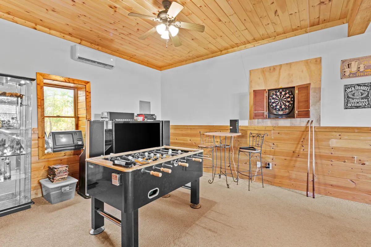 A close-up view of a foosball table and dartboard in a playful, relaxed room with bar stools and a window letting in soft daylight. The scene emphasizes the hands-on, competitive spirit and convivial atmosphere ideal for family tournaments or casual gatherings.