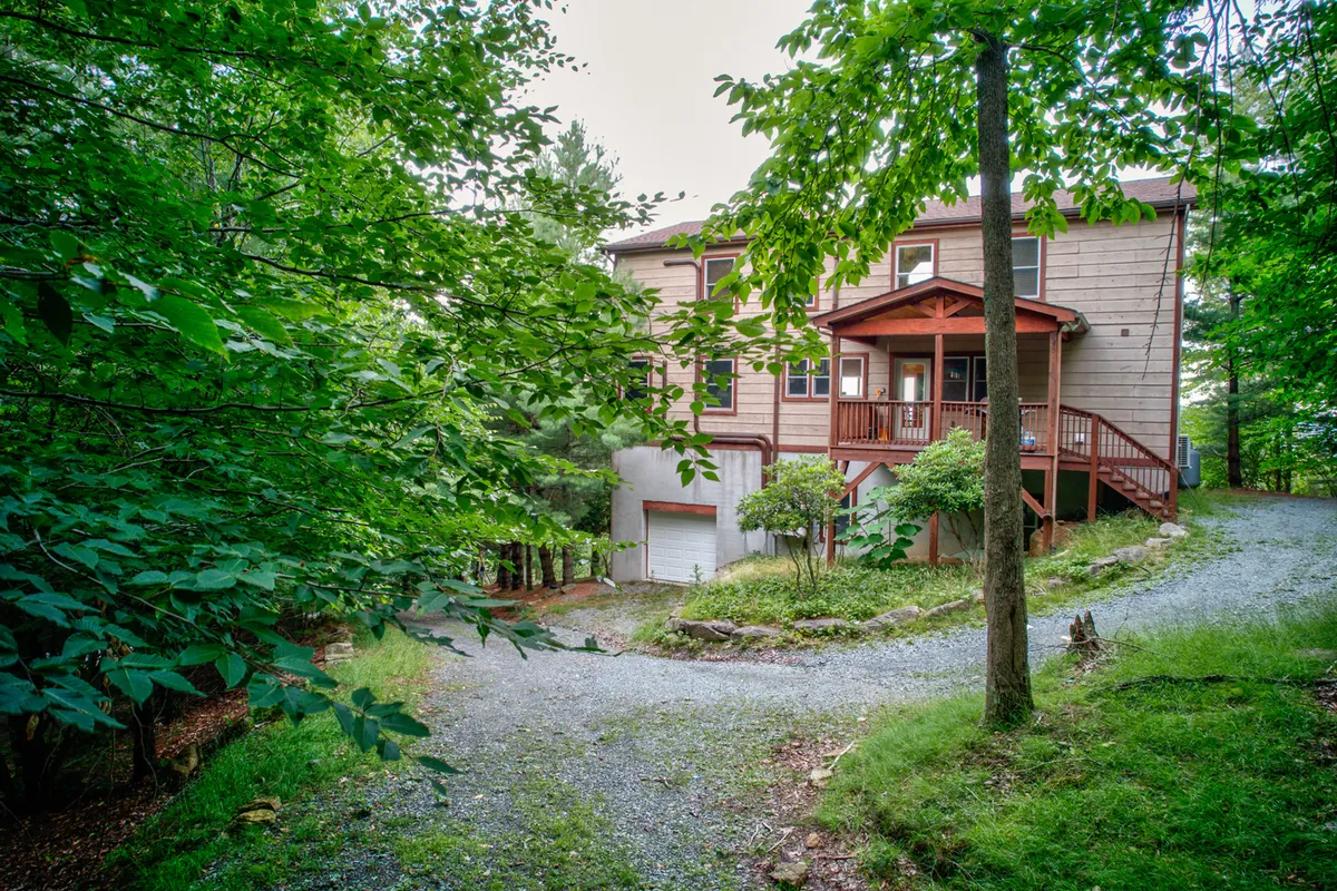 A welcoming exterior shot of the house and its porch, framed by lush greenery. The inviting porch and open yard set the stage for outdoor gatherings, relaxation, and the easy integration of pet-friendly activities.