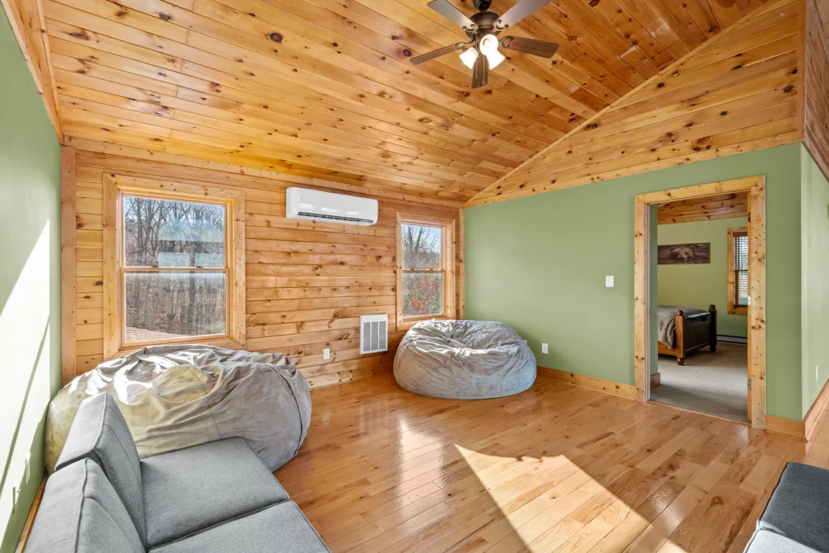 A comfortable lounge area with bean bag chairs, a sofa, and a wooden ceiling, bathed in sunlight from large windows. This space feels inviting and relaxed—ideal for movie nights, unwinding, or sharing laughter after a day of mountain adventures.
